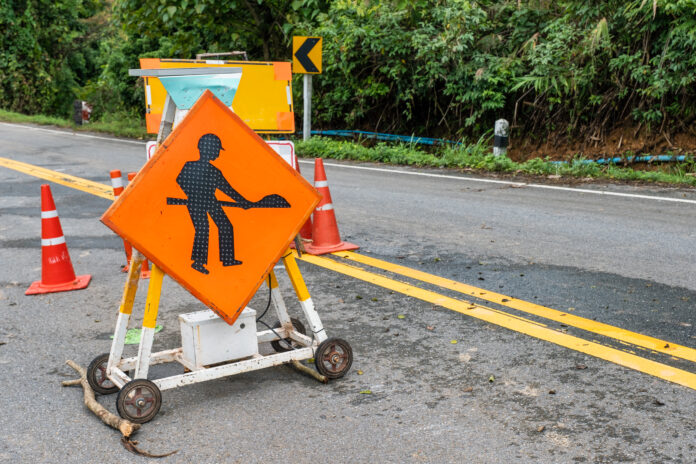 Traffic signs on highway with landslide collapsed road
